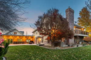 Back of house featuring a lawn, a chimney, a patio, and brick siding