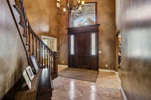 Tiled entryway featuring a high ceiling, arched walkways, a chandelier, and stairway