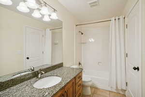 Full bath with light tile patterned floors, vanity, and shower / bath combo