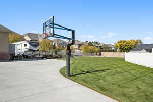 View of basketball court featuring a fenced backyard, a residential view, and basketball hoop