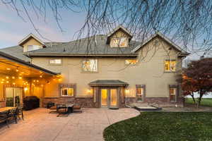 Rear view of house featuring brick siding, a patio, stucco siding, a shingled roof, and a lawn