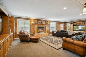 Carpeted living area featuring plenty of natural light, crown molding, a tile fireplace, and recessed lighting