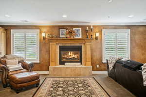 Carpeted living area featuring a fireplace, ornamental molding, recessed lighting, and a textured wall
