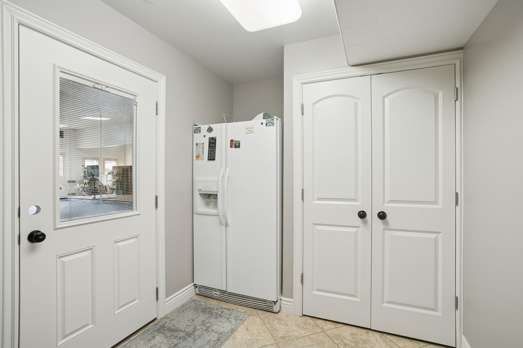 Interior space with white refrigerator with ice dispenser and light tile patterned floors