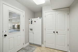 Interior space with white refrigerator with ice dispenser and light tile patterned floors