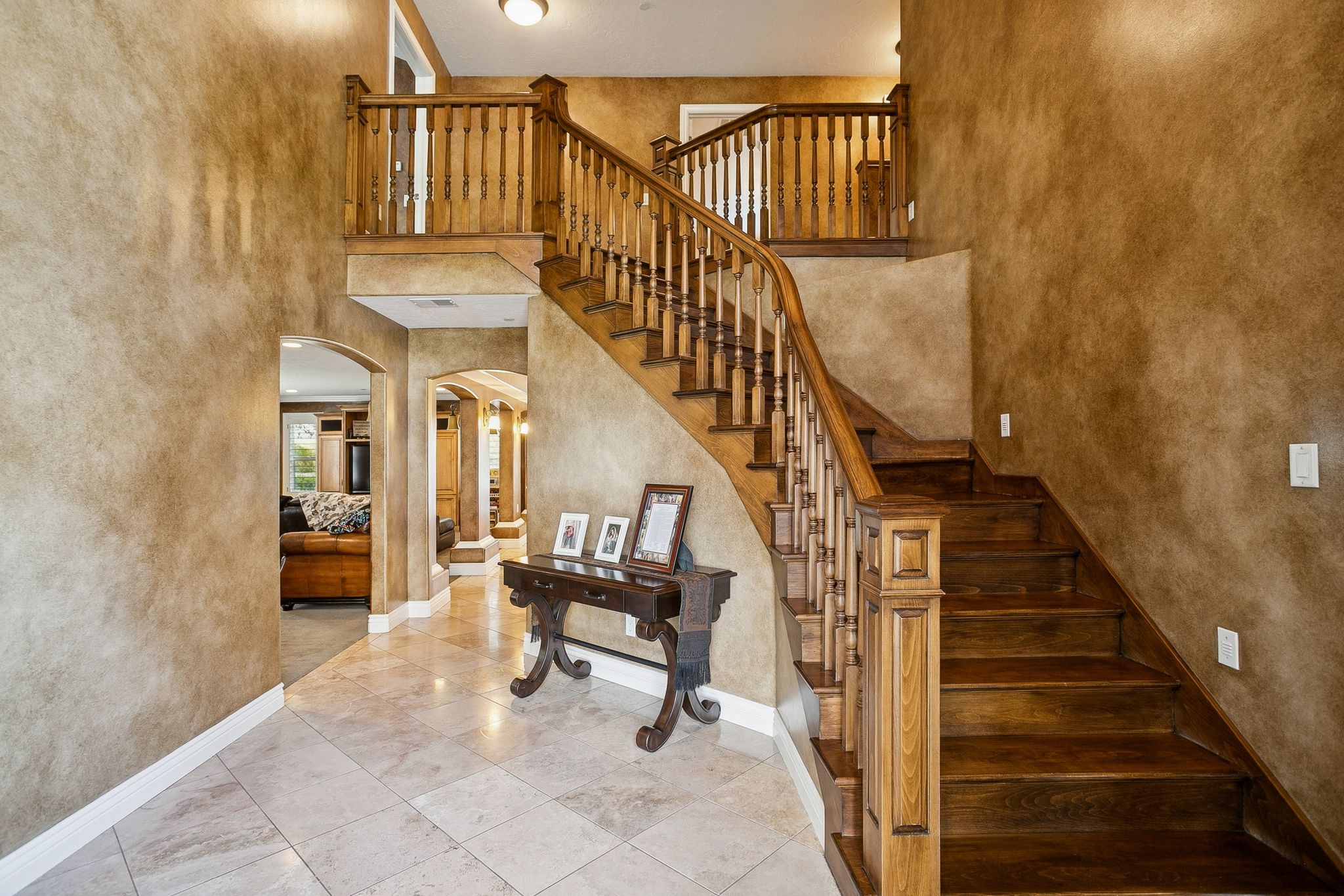 Stairs with a high ceiling, arched walkways, a textured wall, and tile patterned flooring