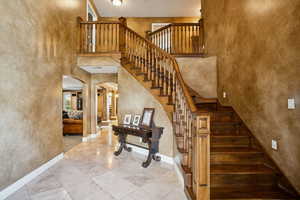 Stairs with a high ceiling, arched walkways, a textured wall, and tile patterned flooring