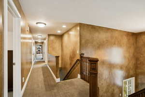 Hall with an upstairs landing, carpet floors, and recessed lighting