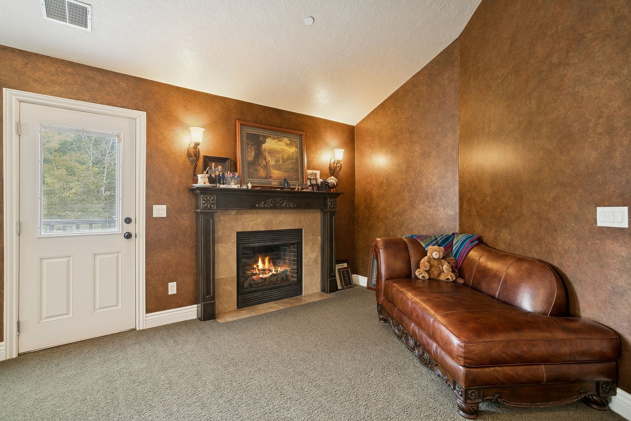 Sitting room featuring lofted ceiling, a tiled fireplace, carpet flooring, and a textured ceiling