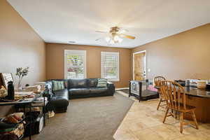 Living area featuring light tile patterned floors, a ceiling fan, and a textured ceiling