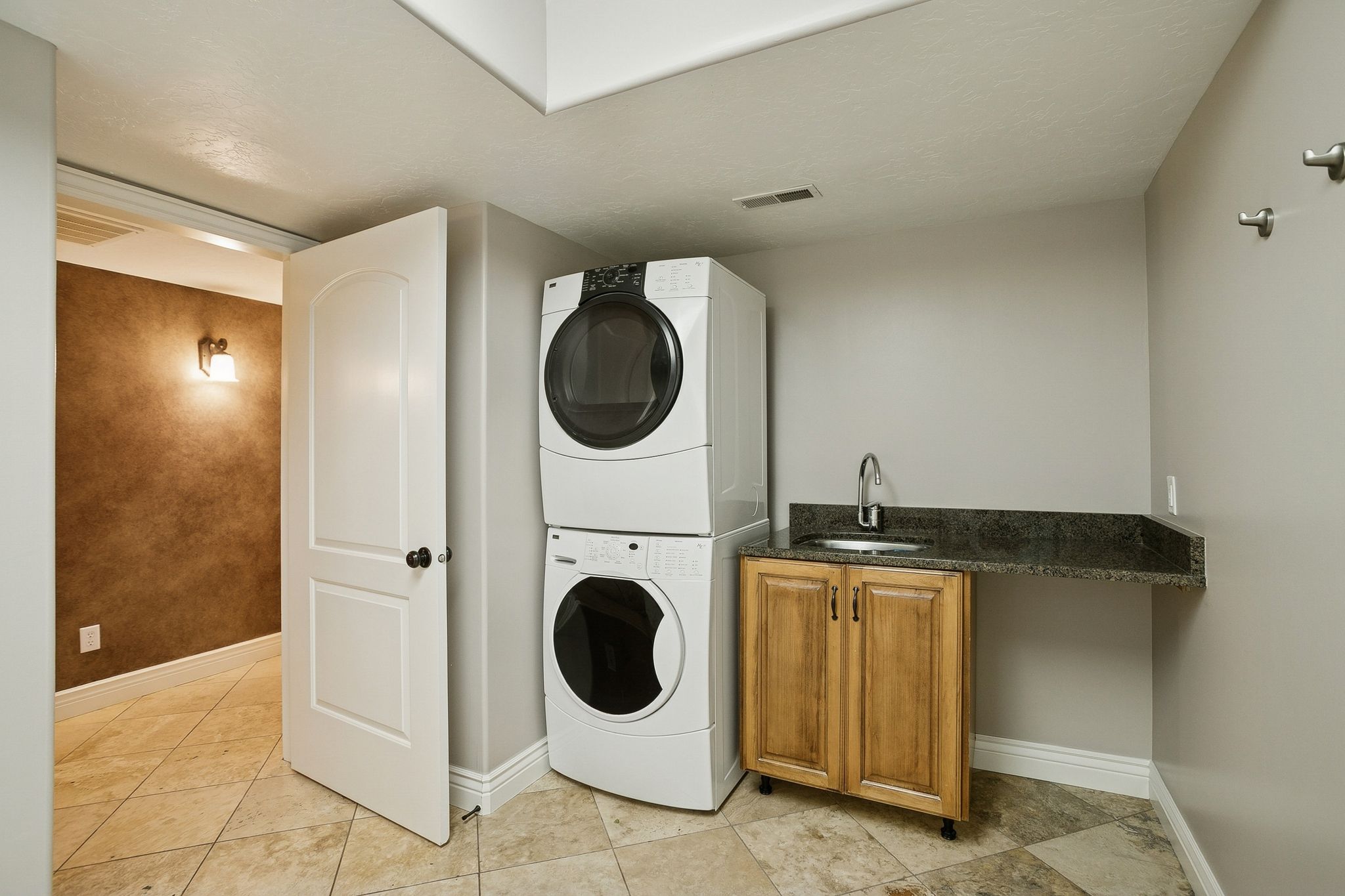 Laundry room featuring estacked washer and dryer, cabinet space, and light tile patterned floors