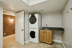 Laundry room featuring estacked washer and dryer, cabinet space, and light tile patterned floors