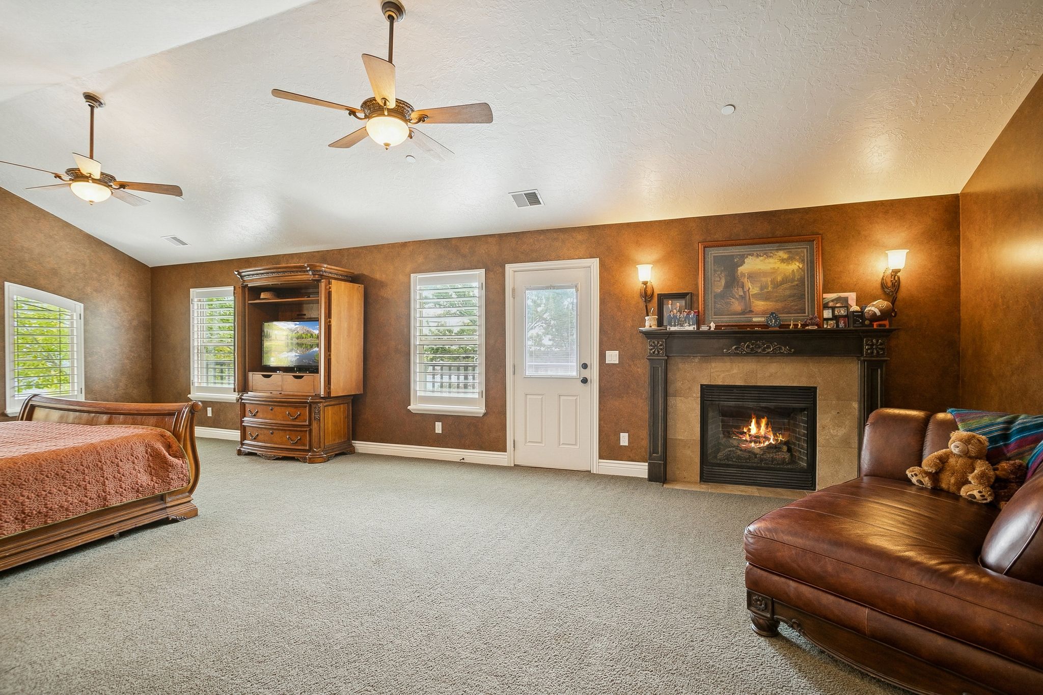 Bedroom with a tile fireplace, carpet floors, lofted ceiling, a textured ceiling, and ceiling fan