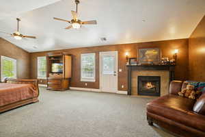 Bedroom with a tile fireplace, carpet floors, lofted ceiling, a textured ceiling, and ceiling fan