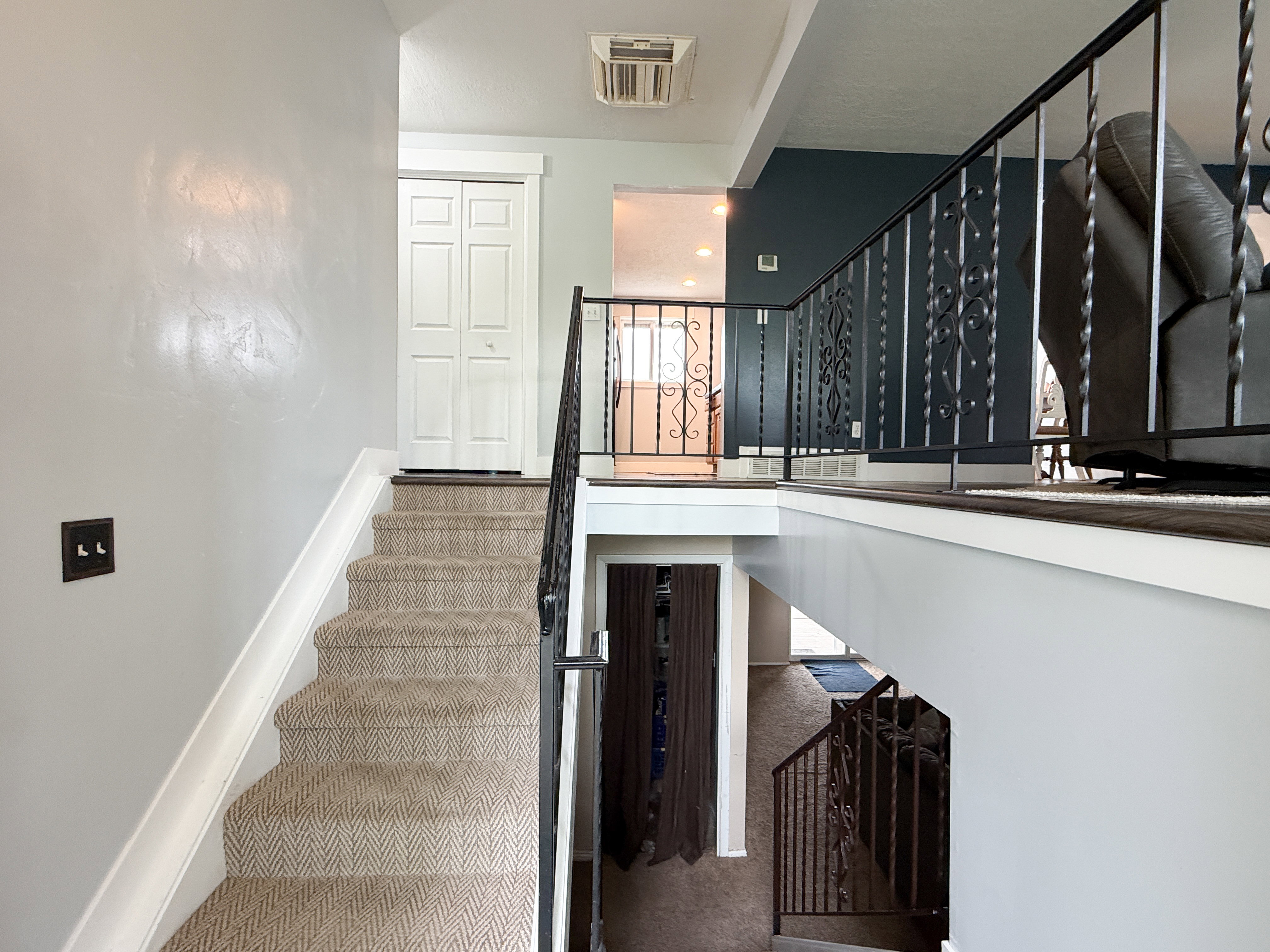 Carpeted staircase with white trim, leading to a landing with a bi-fold door