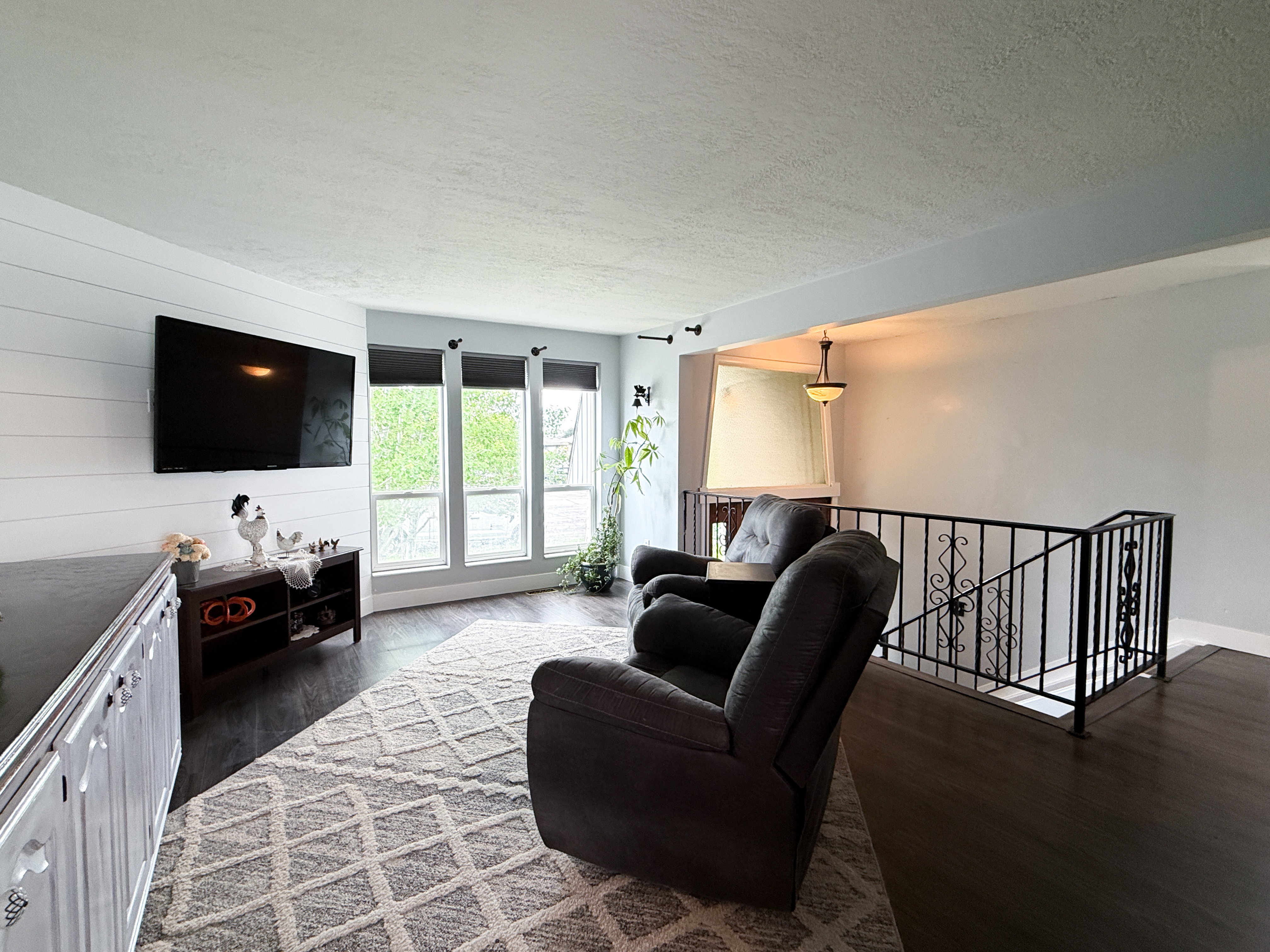 Spacious interior featuring dark wood-finish flooring, a decorative black wrought iron railing, and multiple windows
