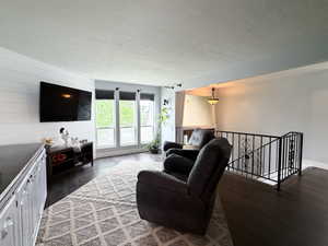 Spacious interior featuring dark wood-finish flooring, a decorative black wrought iron railing, and multiple windows