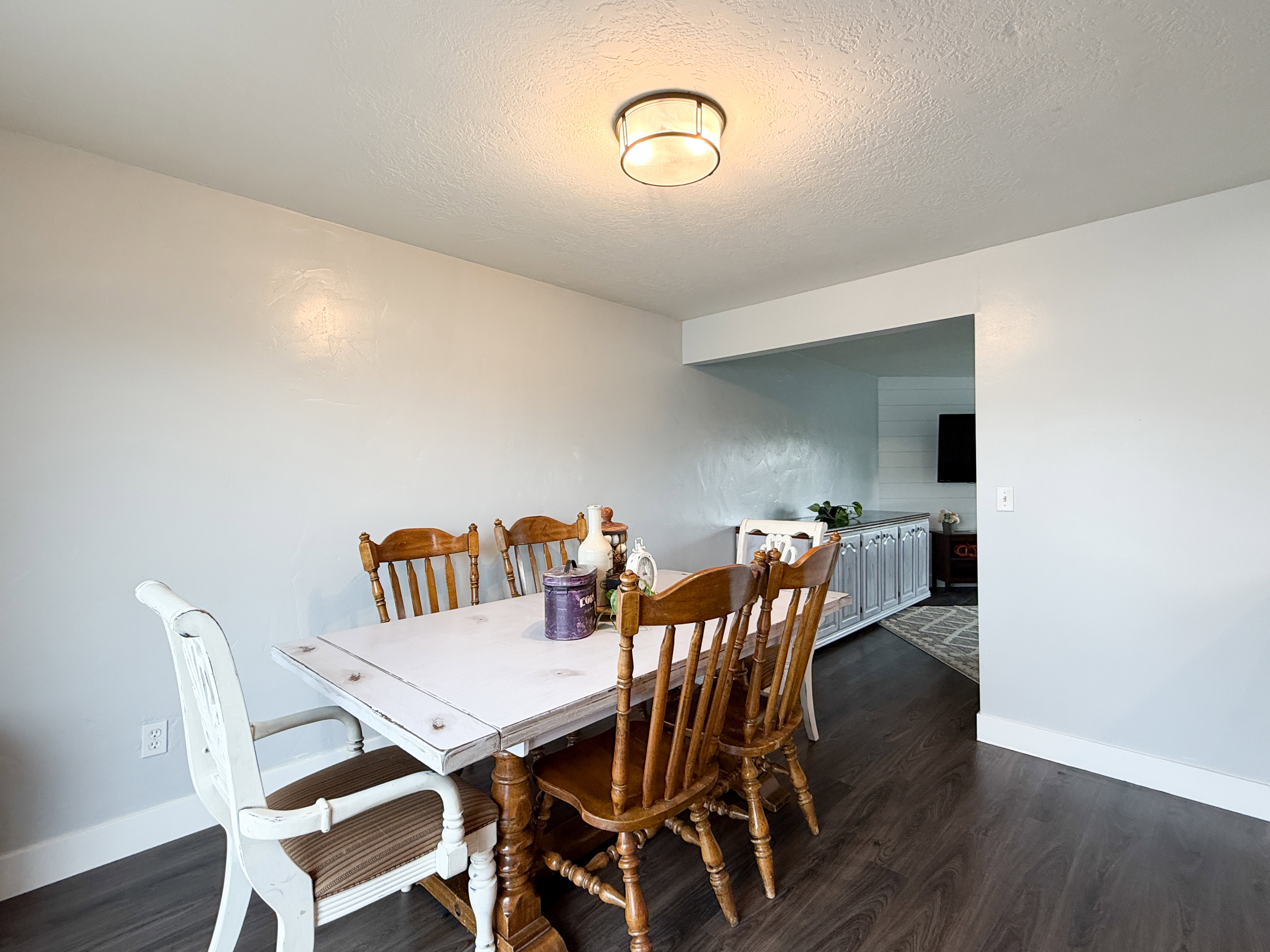 Dining area with dark wood-finish flooring and light-toned walls