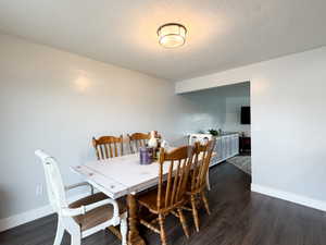 Dining area with dark wood-finish flooring and light-toned walls