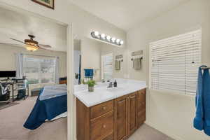 Ensuite bathroom featuring vanity, light carpet, and a ceiling fan