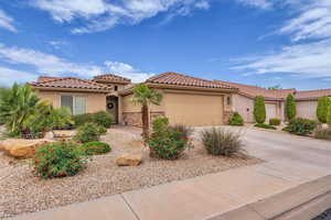 Mediterranean / spanish-style house with stucco siding, an attached garage, driveway, stone siding, and a tiled roof