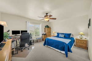 Bedroom featuring an office area, light colored carpet, and a ceiling fan