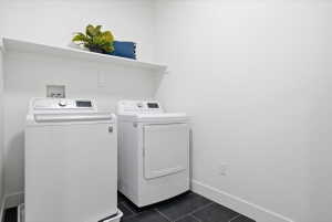Laundry area with dark tile patterned floors and independent washer and dryer