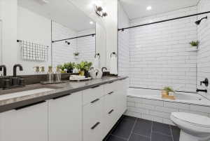 Full bath with double vanity, tiled shower / bath, and dark tile patterned flooring