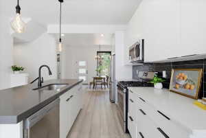 Kitchen featuring white cabinetry, stainless steel appliances, pendant lighting, and modern cabinets