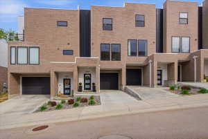 Contemporary townhome with brick exterior, concrete driveway, and an attached garage