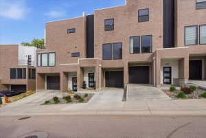 Modern townhouse featuring a garage, driveway, and brick siding