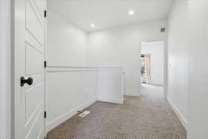 Hallway with light carpet and recessed lighting