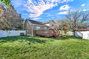 Rear view of house featuring a fenced backyard, a deck, and brick siding