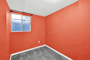 Spare room featuring dark colored carpet and a textured ceiling