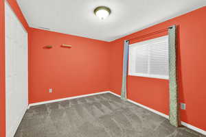 Unfurnished bedroom with dark carpet, a closet, and a textured ceiling