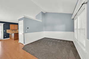 Empty room featuring plenty of natural light, lofted ceiling, and dark wood-style flooring