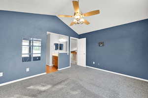 Unfurnished bedroom with lofted ceiling, ensuite bath, light colored carpet, and a ceiling fan