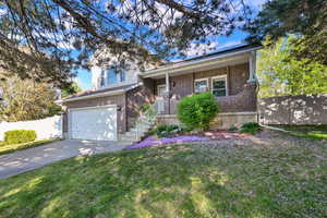 View of front of property with covered porch, brick siding, driveway, and an attached garage