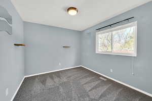 Empty room featuring dark colored carpet and baseboards