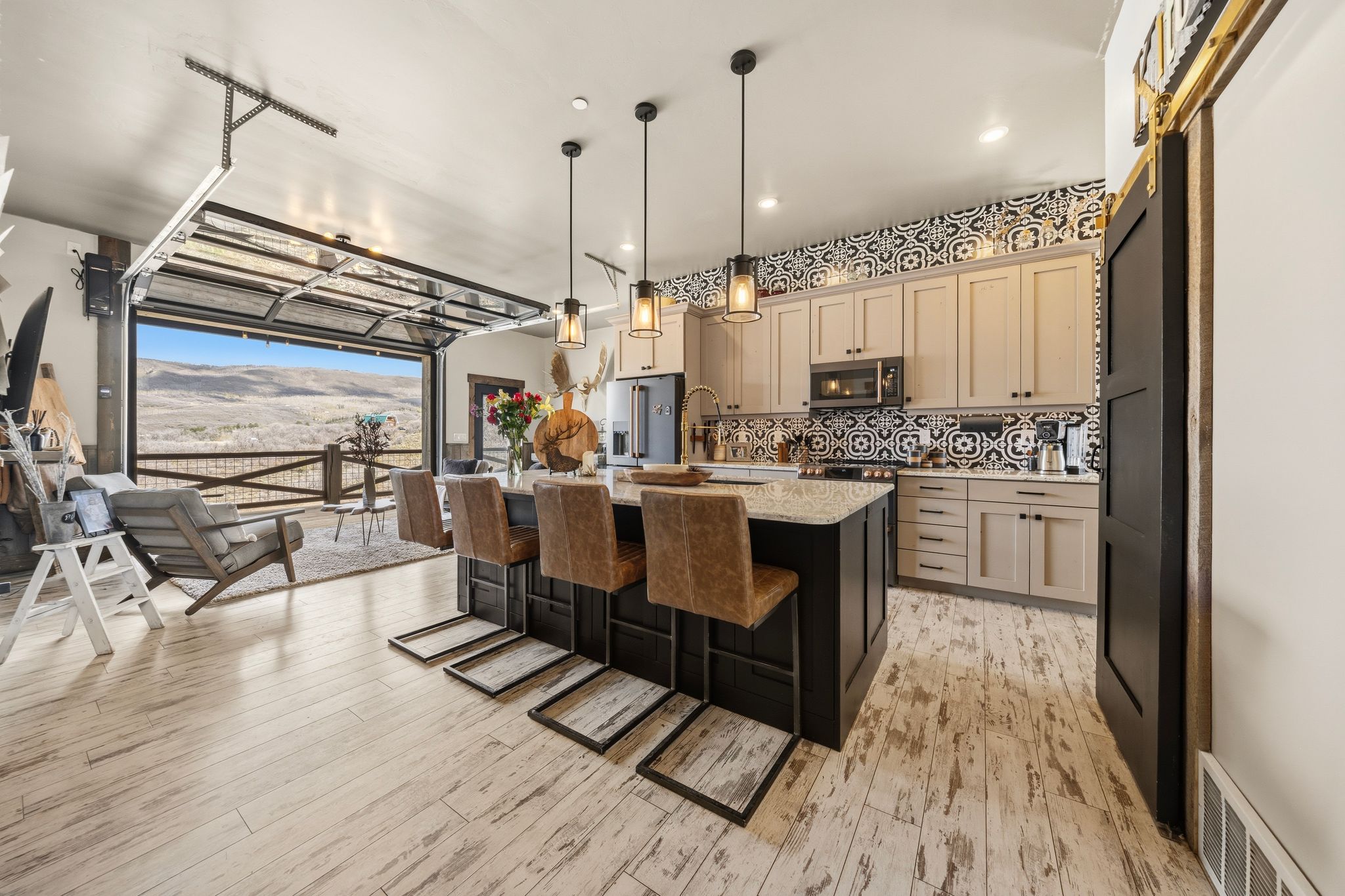 Kitchen featuring a mountain view, a breakfast bar, a kitchen island with sink, light stone counters, and decorative light fixtures