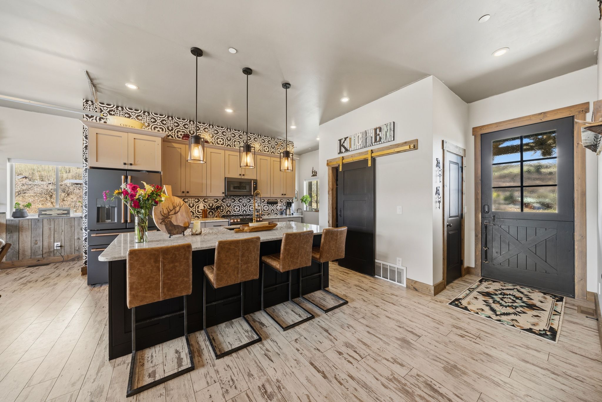 Kitchen with plenty of natural light, a kitchen island with sink, stainless steel appliances, and light stone counters
