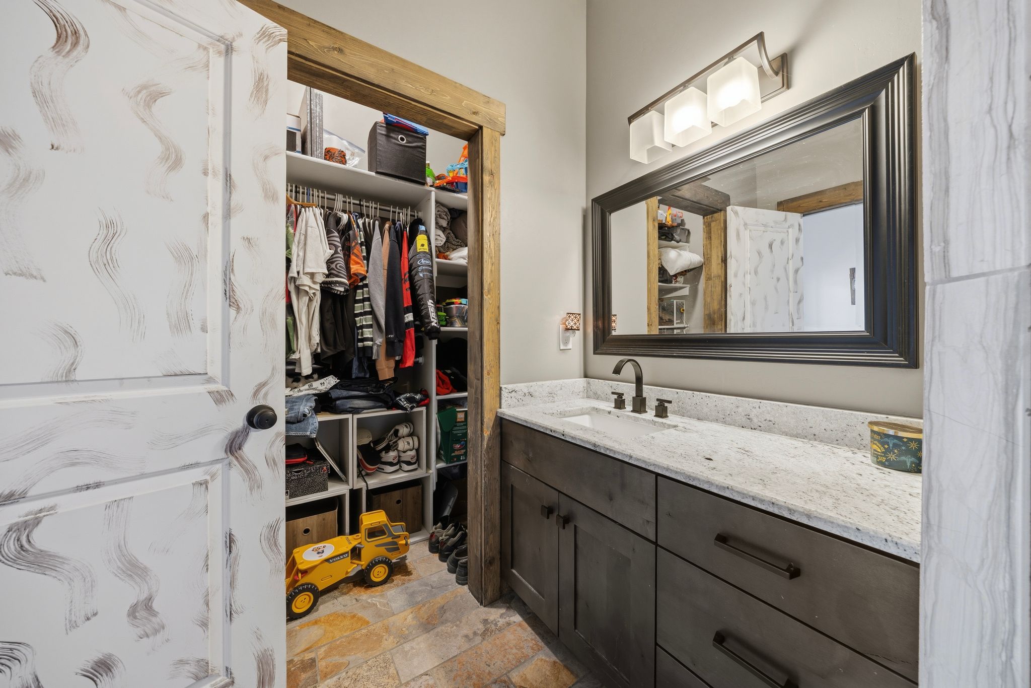 Full bath featuring vanity, stone finish floors, and a spacious closet