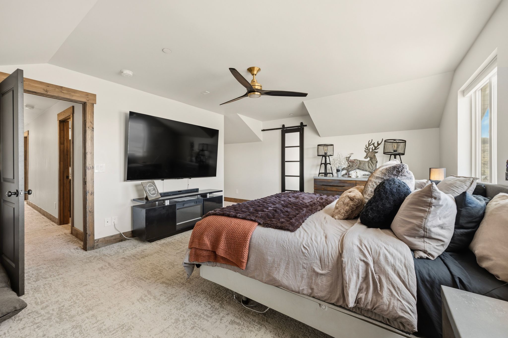 Bedroom with vaulted ceiling, a barn door, light colored carpet, and ceiling fan