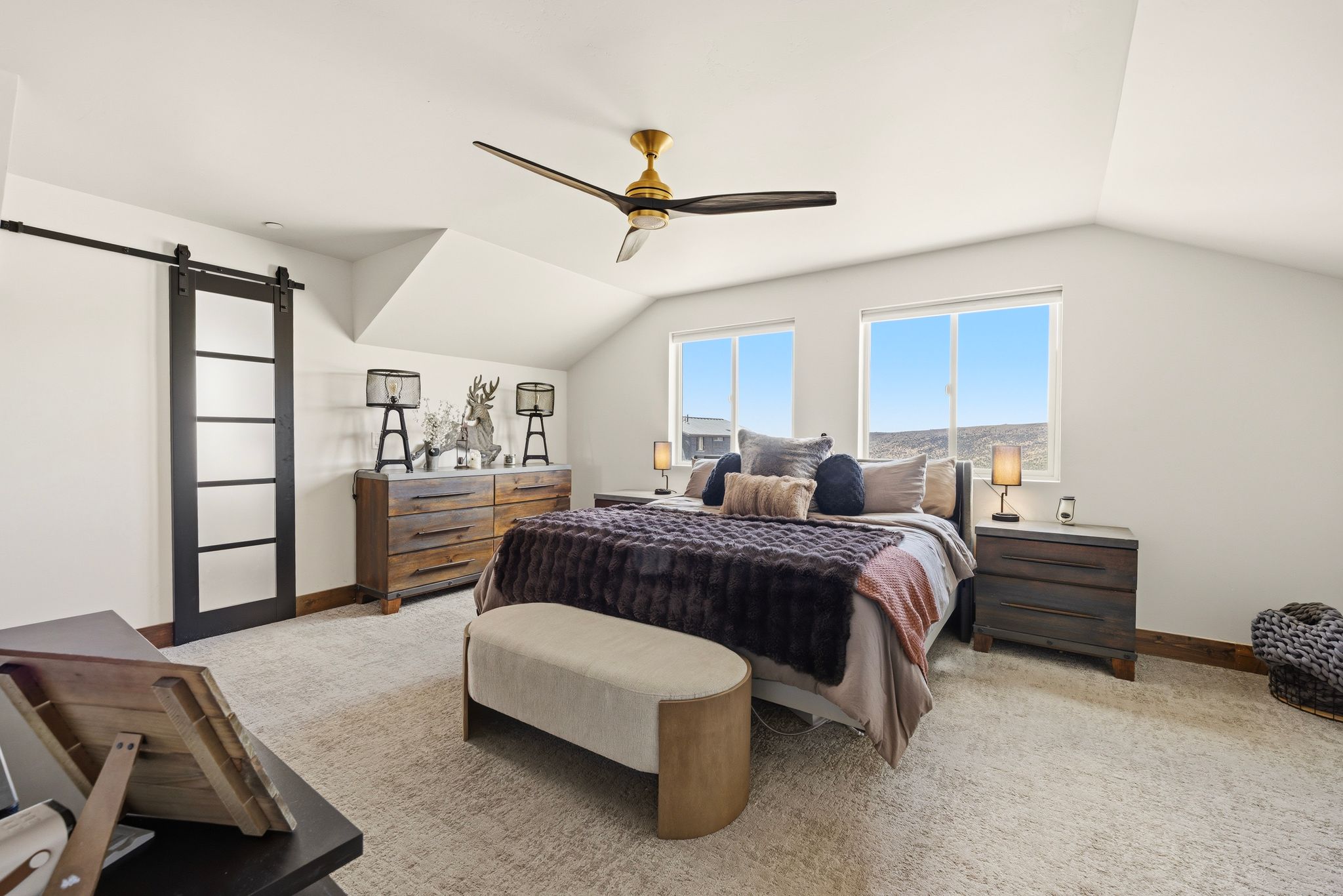 Bedroom with a barn door, light colored carpet, lofted ceiling, and a ceiling fan