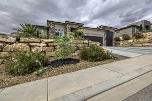 Prairie-style house with stone siding, a garage, concrete driveway, and stucco siding
