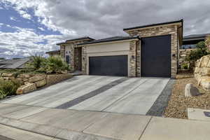 Prairie-style house featuring a garage, stone siding, driveway, and stucco siding