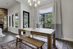 Dining area with wood tiled floors, healthy amount of natural light, hanging lights, and a stone fireplace