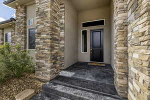 Entrance to property with stucco siding and stone siding