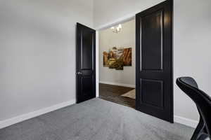 Home office featuring dark colored carpet and hanging lights