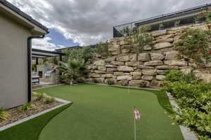 View of yard with an area to practice putting, a patio, and area for grilling